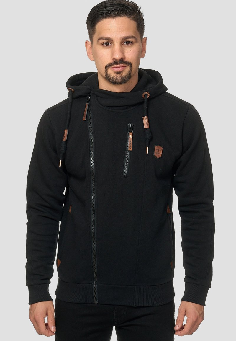 Sudadera negra con cremallera fabricada en un tejido suave, con un cuello alto, detalles de cuero, dos bolsillos con cremallera y puños de canalé.