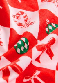 Tissu rouge avec un motif répétitif d'ornements de Noël verts et blancs, de cannes en sucre et de nœuds, créant un design festif.