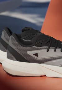 Sive tene za sport s mrežastim i sintetičkim premazom, crnim naglascima i bijelim LIGHTSTRIKE potplatom. Obavezivanje s podstavljenim obrubom.