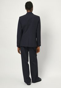 Navy pinstripe suit met een gestructureerde blazer met brede revers en bijpassende loszittende broek, vervaardigd uit een textuur-stof.