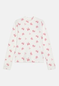 Langermet skjorte laget av ribbet stoff, hvit med rosa sløyfemønster over hele. Har rund halslinning og tettsittende ermer.
