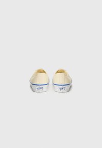 Canvas sneakers in light yellow, with white soles and blue accents. Low-top design featuring a classic, simple style.