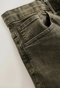 Grüne Jeans aus Denim mit strukturierter Oberfläche, ausgestattet mit einer Gesäßtasche und Nähten. Hergestellt aus Baumwolle und betont ein lässiges Design.