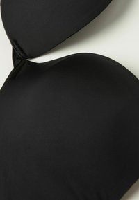Zwarte gep padded beha van gladde stof, met voorgevormde cups en verstelbare bandjes. Heeft een naadloos ontwerp en subtiele stikdetails.