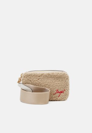 Pochette en polaire beige avec une surface texturée, dotée d'une fermeture éclair dorée et d'une sangle crème. Un texte brodé rouge dit "Joyeux !"
