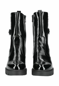 Bottines en cuir verni noir avec une finition brillante, fermeture éclair sur le côté et semelles en caoutchouc épaisses. Présente un accent en boucle sur le côté.