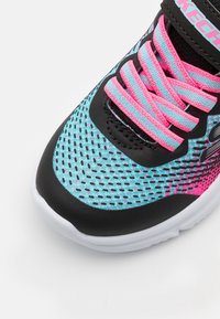 Chaussure de sport noire et rose avec une tige en maille présentant des accents turquoise, une surface texturée, des lacets roses et une semelle blanche.