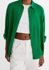 Groene overhemd met kraag, gemaakt van lichtgewicht stof. Draag het over een witte crop top en combineer het met witte broek.