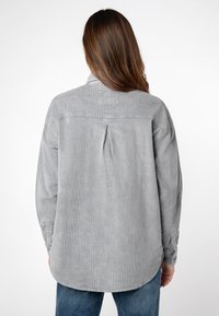 Grijs corduroy shirt met een relaxte pasvorm, rugplooidetail en lange mouwen met knopenmanchetten. Soepele textuur en afgeronde zoom.