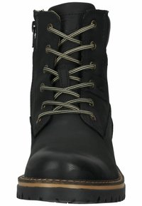 Black leather ankle boot with round toe, contrasting beige stitching, metal eyelets, and fabric laces. Features a side zipper and textured sole.