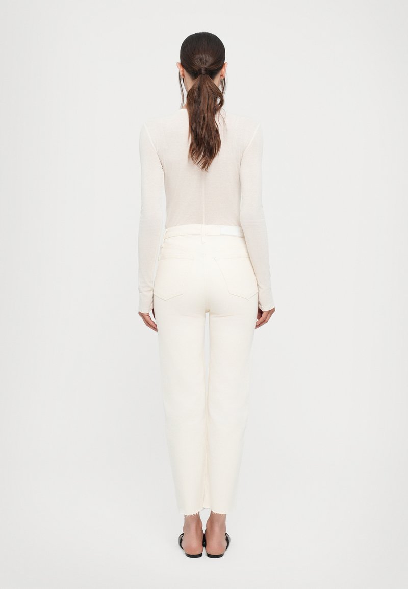 Haut ajusté beige clair à manches longues et pantalon droit blanc cassé avec ourlet brut, fabriqué en tissu doux, vu de dos.