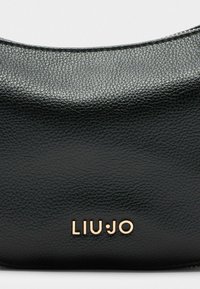 Mustvalge nahast käekott, millel on sile, tekstureeritud pind ja kõver ülaosa. Kuldsed "LIU•JO" logo paremas alanurgas.