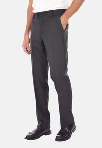 Pantaloni grigi su misura con un design elegante, vita media, passanti per cintura, tasche laterali e una texture liscia. Indossati con mocassini neri.