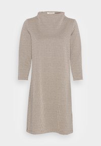 Robe à motifs camouflage beige avec un col haut et des manches trois-quarts, dotée d'une coupe ample et de fentes latérales pour faciliter les mouvements.