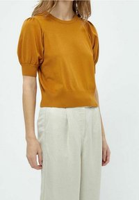 Senapsgul stickad tröja med korta puffärmar, ribbade muddarna och nederkant, ihopparad med ljusbeiga hög midja byxor. Mjuk textur.