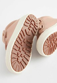 Lyserøde lædersneakers med en struktureret gummisål, der har stjernemønstre og en hvid mellemsål. Designet inkluderer en rund tå og stroplukning.
