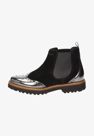 Botín Chelsea de ante negro con punta metálica plateada, detalles perforados, paneles elásticos laterales y suela de goma texturizada.