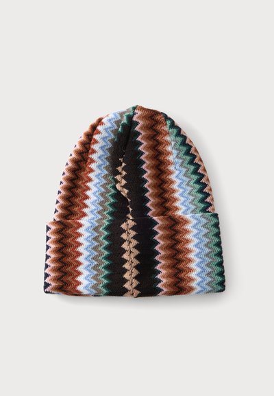 Bonnet tricoté avec motif en zigzag aux rayures vertes, bleues, marron, beige et noires sur fond blanc.
