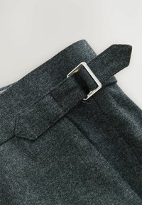 Grau meliertes Wollmischgewebe mit einem Gürtelschlaufe und silberner Metallschnalle. Verfügt über eine glatte Textur und ein maßgeschneidertes Design für eine taillierte Optik.
