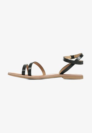 Sandalia negra con dos correas anchas y planas, y una correa en el tobillo. Cuero suave con un patrón de cocodrilo. Suela plana, diseño minimalista.