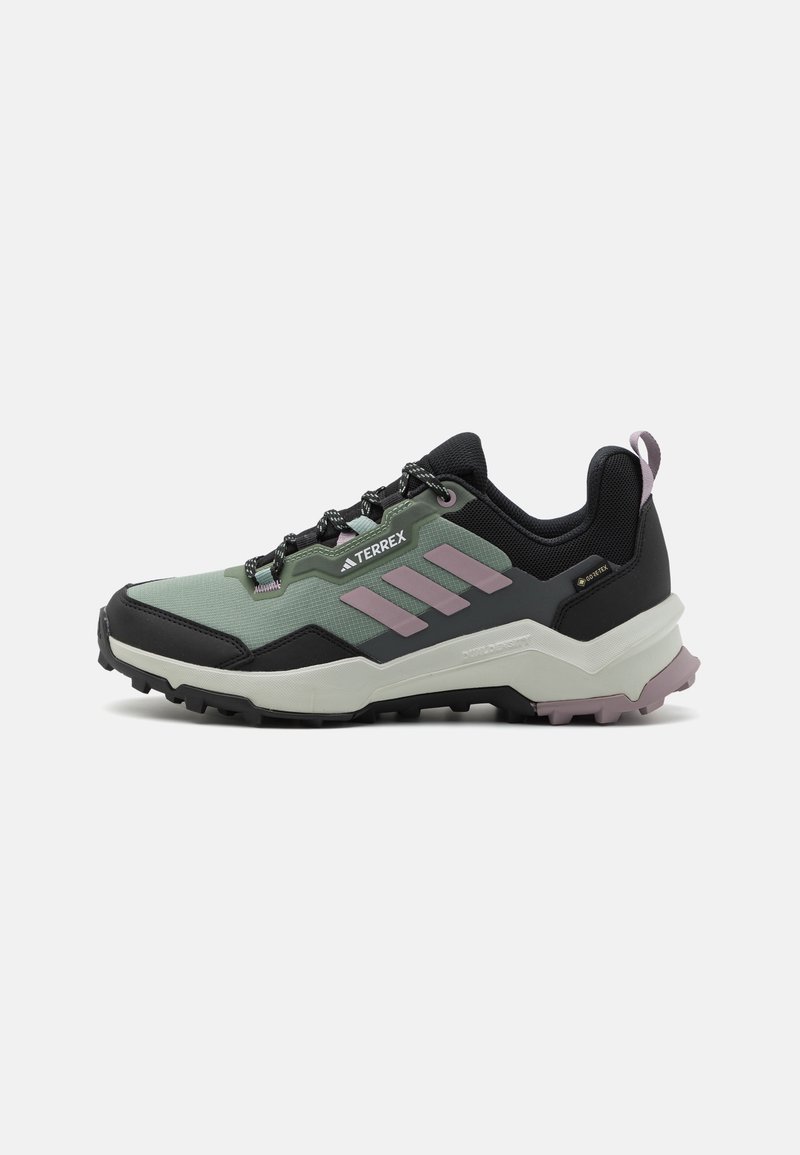Chaussure de randonnée extérieure en vert, noir et rose avec une semelle robuste, fermeture à lacets et empeigne en mesh respirant marquée Terrex et Gore-Tex.