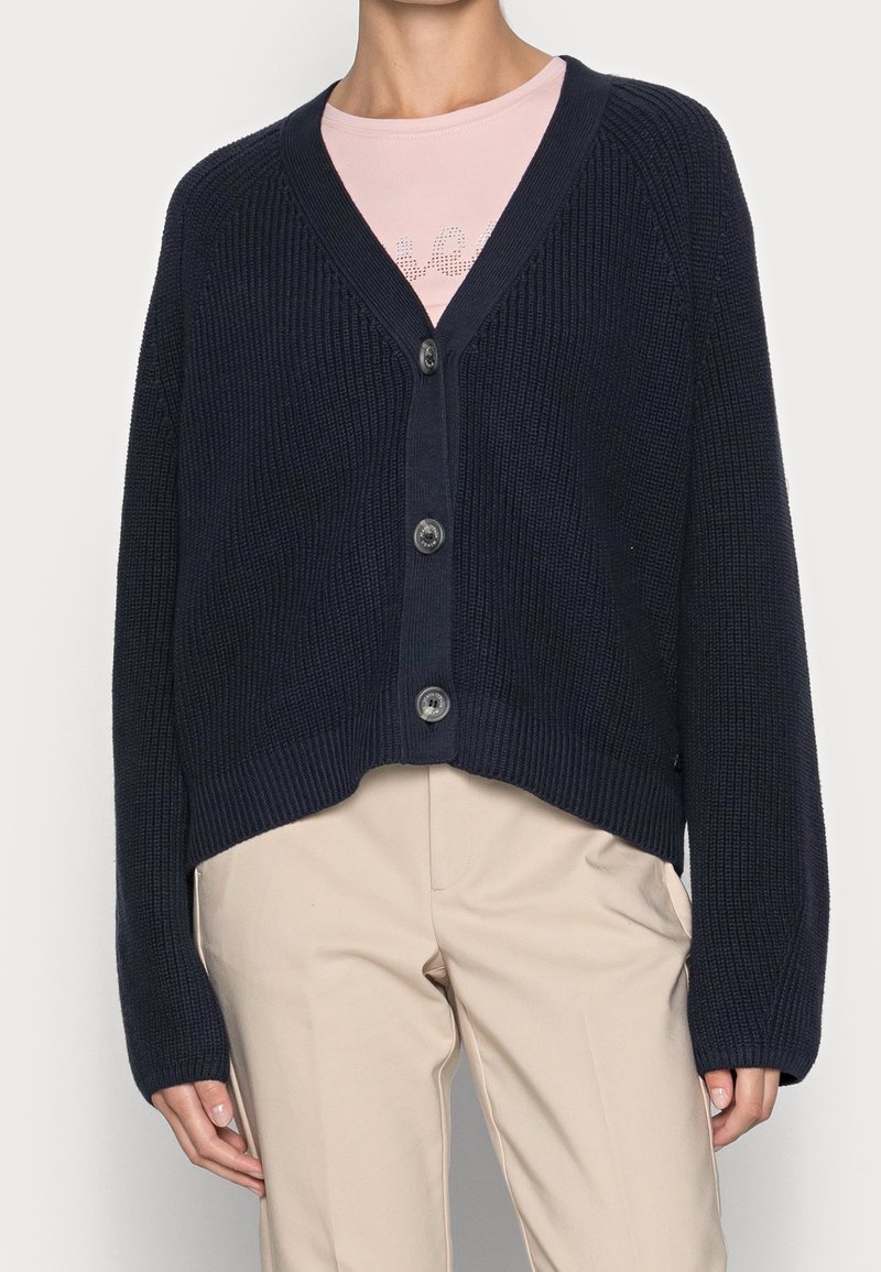 Cardigan tricoté bleu marine avec un col en V, des manches raglan et une fermeture à boutons sur quatre. Présente un design court avec un ourlet et des poignets côtelés.