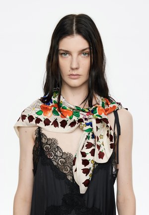 Bufanda de seda con patrones florales y de tulipanes coloridos sobre un fondo crema, drapeada alrededor del cuello, combinada con una blusa de encaje negra.