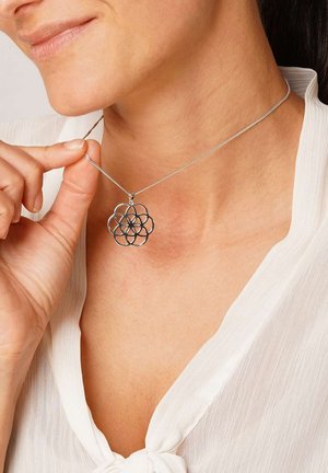 Silberne Anhängerkette mit einem Blumenmotiv und einem filigranen geometrischen Muster, aufgehängt an einer dünnen Kette.