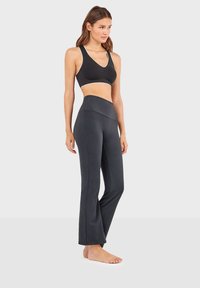 Zwarte sport-bh met witte accenten en hoge zwarte legging, beide van rekbare stof. De legging heeft een uitlopende stijl.