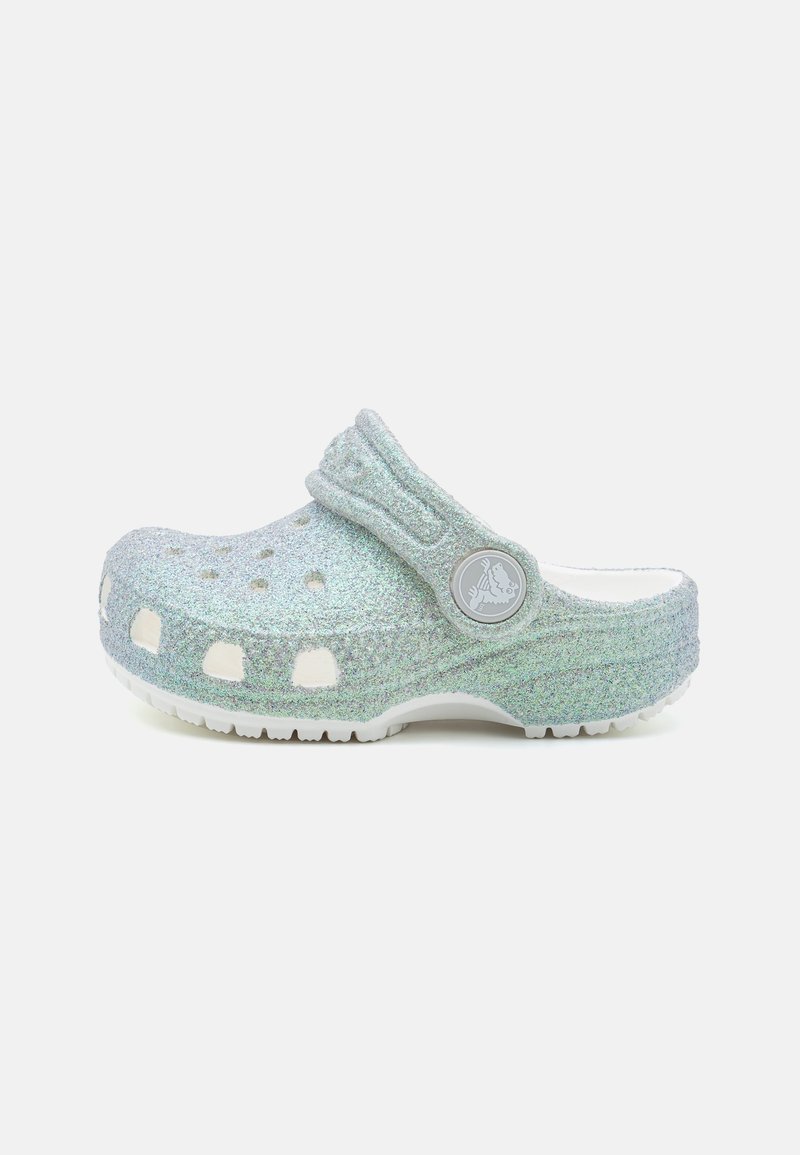 Sabot bleu clair pailleté à enfiler avec des trous de ventilation et une bride arrière avec un logo circulaire sur une semelle blanche.