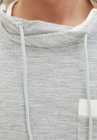 Hellgrauer Hoodie aus strukturiertem, geripptem Stoff, mit hohem Kragen und einem Kordelzug mit flachem Webmuster; enthält eine kleine Brusttasche.