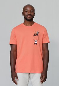 Korallefarbiges Baumwoll-T-Shirt mit kurzen Ärmeln, das ein grafisches Design von Pandas in einer Taschenoptik zeigt. Glatte Textur, Rundhalsausschnitt, lockere Passform.