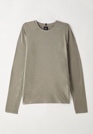 Long-sleeved, crew neck top in light gray fabric. Features flat seams and side slits for ease of movement, with a smooth, soft texture.