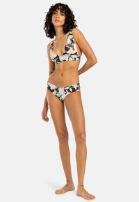 Blommig bikini-set med en djup V-ringning på överdelen och lågt skurna trosor. Mörk bakgrund med färgglada blommor i nyanser av rosa och blått.