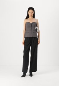 Šedý top bez ramínek ve stylu peplum s knoflíky, nošený s černými kalhotami širokého střihu a špičatými černými podpatky, doplněný malou stříbrnou kabelkou.