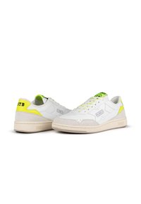 Zapatillas blancas con acentos en verde lima, materiales de ante y cuero, diseño de cordones, suelas texturizadas y un logo en el lado y el talón.