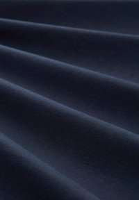 Tessuto jersey blu scuro, superficie liscia, con un morbido drappo e una leggera lucentezza, caratterizzato da pieghe e piegamenti sottili. Materiale resistente e elastico.