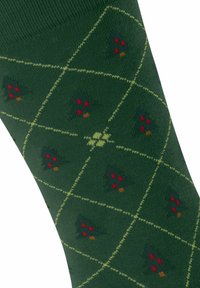 Grüne Socken mit einem Diamantmuster, das kleine, mehrfarbige Weihnachtsbäume und kontrastierende gelbe Umrisse zeigt. Glatte Stricktextur.