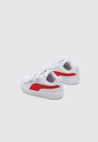 Sneaker bianchi con un accento rosso sui lati, parte superiore texturizzata, chiusura con lacci e suola in gomma con il logo Puma.