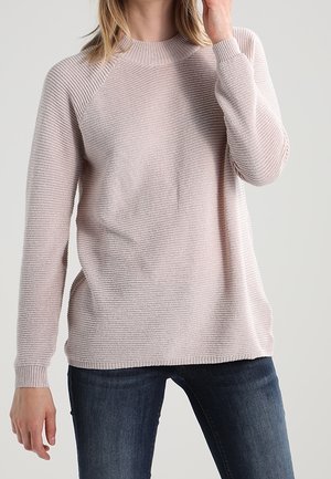 Lys pink strikket sweater med ribbet tekstur, rund halsudskæring og raglanærmer, parret med mørk denim jeans.