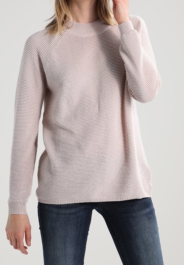 Helles rosa gestricktes Sweatshirt mit geribbelter Struktur, Rundhalsausschnitt und Raglanärmeln, kombiniert mit dunkelblauen Jeans.
