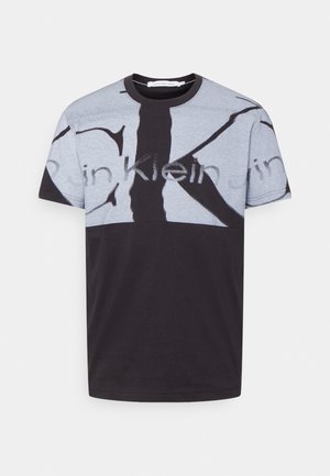 Kurzärmeliges T-Shirt mit Rundhalsausschnitt, untere Hälfte schwarz und obere Hälfte grau, mit großen abstrakten schwarzen Buchstaben und zartem "Calvin Klein Jeans"-Schriftzug.