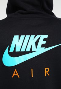 Svart hoodie med en ljusblå Nike-logotyp och ordet "AIR" i orange. Tillverkad av bomull med en mjuk текстur. Enkel, modern design.