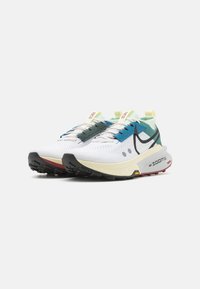 Par de zapatos de correr Nike ZoomX en blanco, verde azulado y azul, con suelas negras, diseño con cordones y logotipos prominentes de Nike en los lados.
