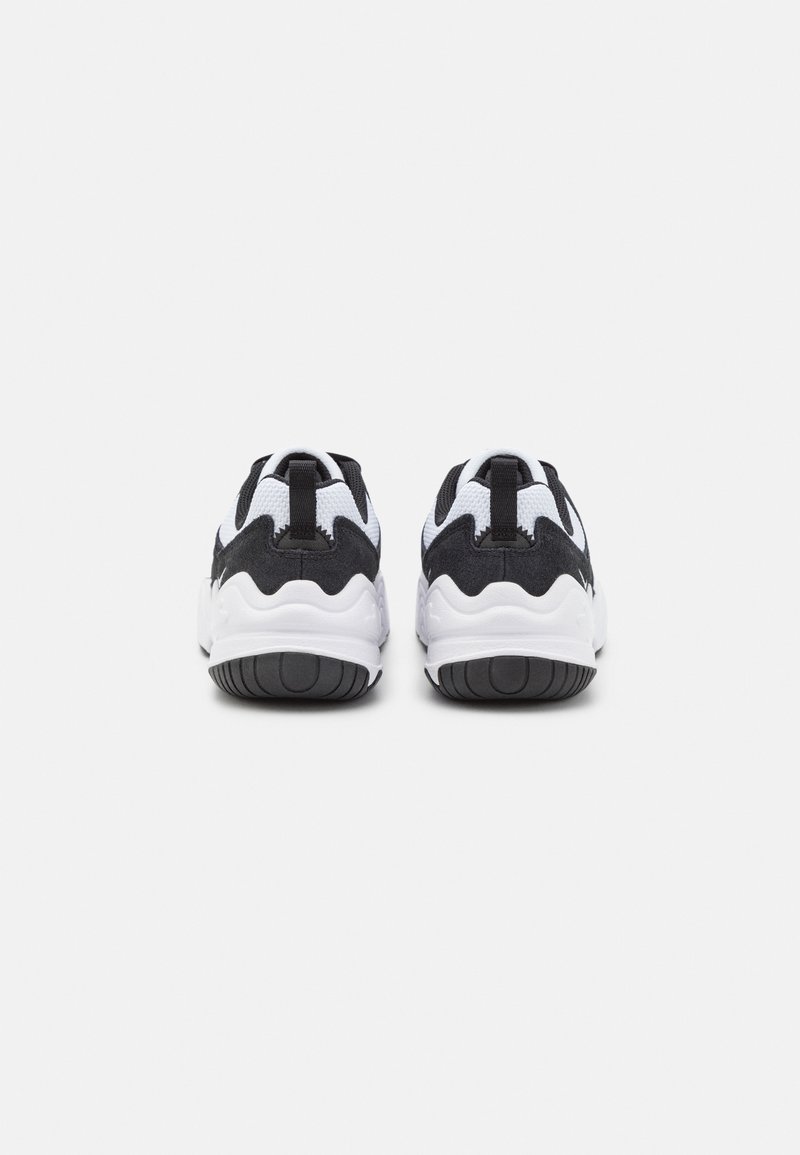 Des chaussures de sport noires et blanches présentent une tige en maille, des accents de design ondulés et une semelle en caoutchouc avec un motif de traction texturé.