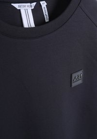 T-shirt nera in cotone con scollatura tonda, vestibilità regolare, con un'etichetta logo testurizzata sul petto e sulle cuciture delle spalle.