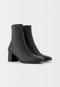Czarne botki za kostkę wykonane z gładkiej skóry, z blokowym obcasem i szpiczastym noskiem, z subtelnymi przeszyciami na cholewce.