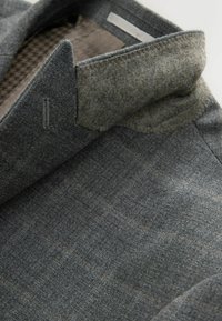 Grau Wolle Blazer mit einer strukturierten Oberfläche, ausgestattet mit einem strukturierten Kragen und einem dezenten Karomuster. Innenfutter aus einem kontrastierenden Stoff.