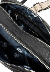 Czarna skórzana torba o fakturowanej powierzchni, z wieloma komorami na zamek oraz granatowym wnętrzem z wzorem jasnokolorowych logo.