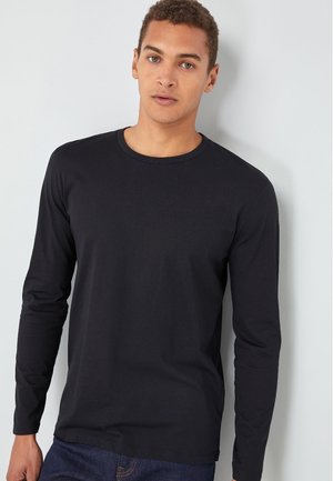 Sort langærmet t-shirt i bomuld med rund hals, tætsiddende ærmer og en glat tekstur, båret sammen med blå jeans.